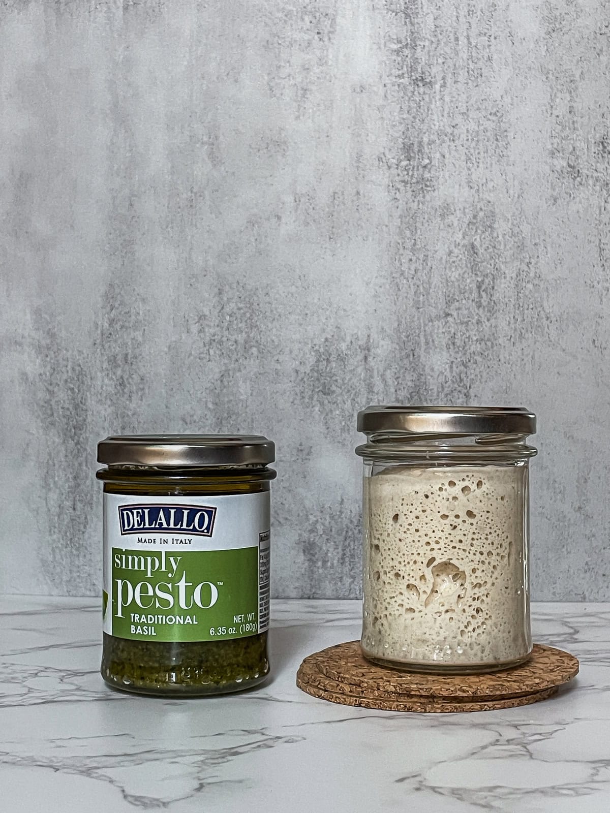 Two glass jars, one filled with sourdough starter and the other with pesto.