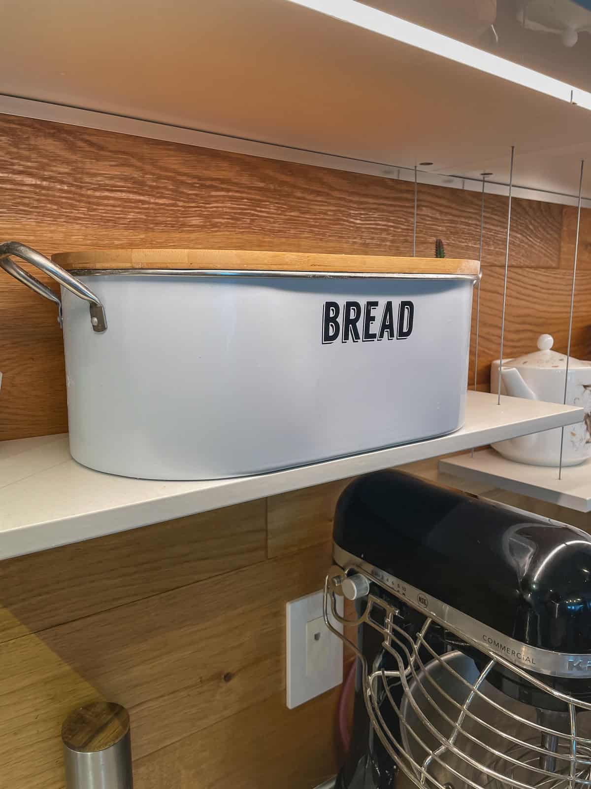 Sourdough bread stored in a bread box on a kitchen shelf.