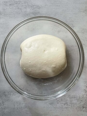 Folded bread dough during bulk fermentation in a glass bowl.
