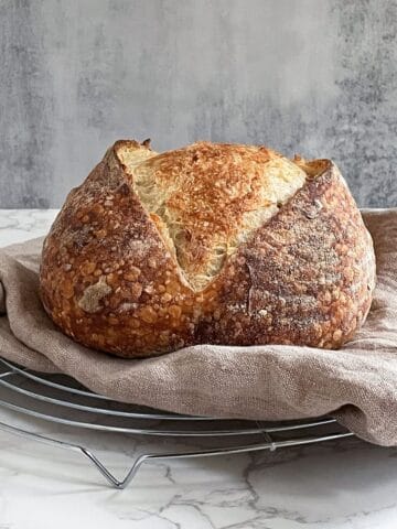 Sourdough loaf on a wire rack, with a towel underneath.