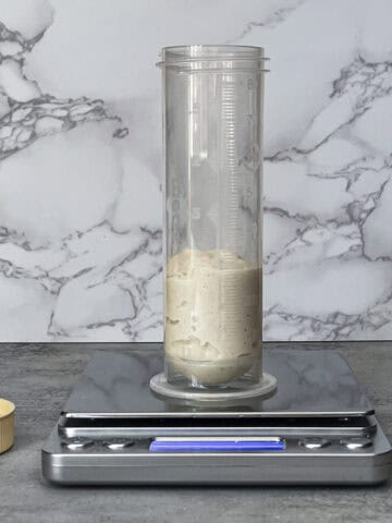 Aliquot jar with dough on a digital scale, ready to track percentage rise during sourdough bulk fermentation.