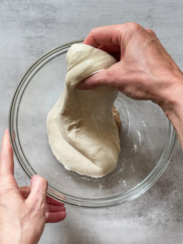 Sourdough dough stretched over a glass mixing bowl.