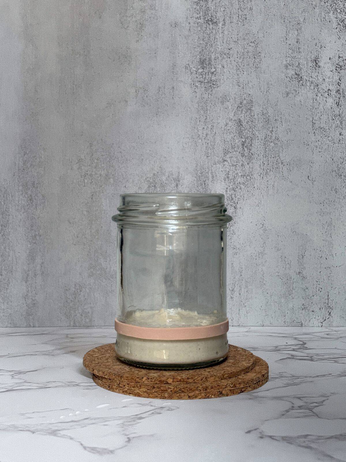 Sourdough starter in a jar marked with a beige rubber band.