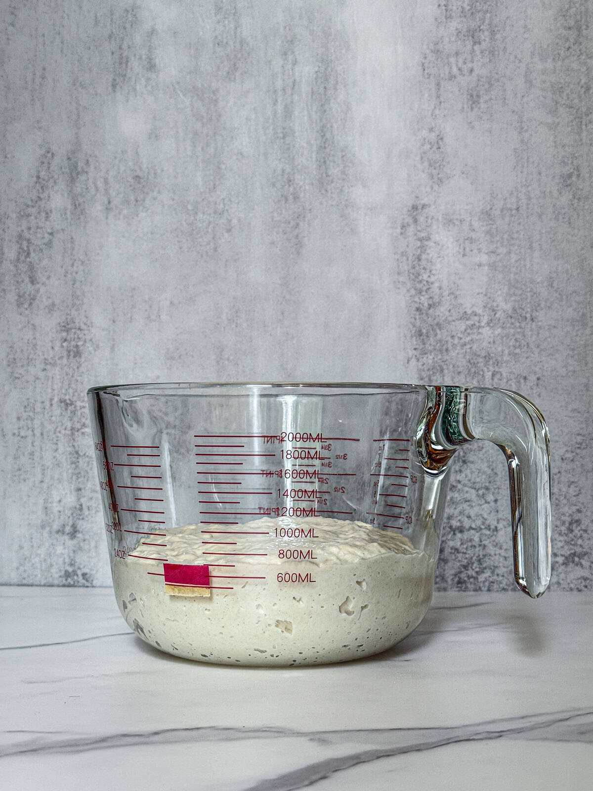 Sourdough dough in a measuring cup with a marked starting volume.