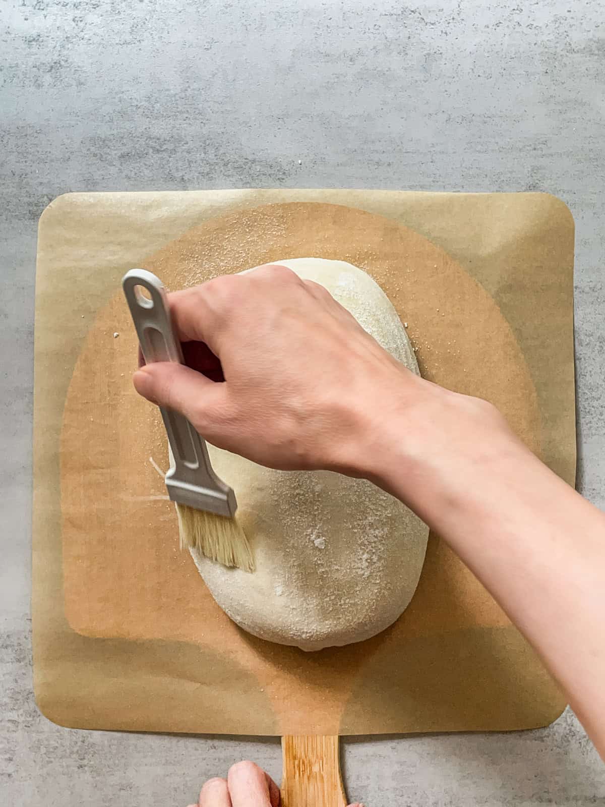 Hand brushing white rice flour with a pastry brush.