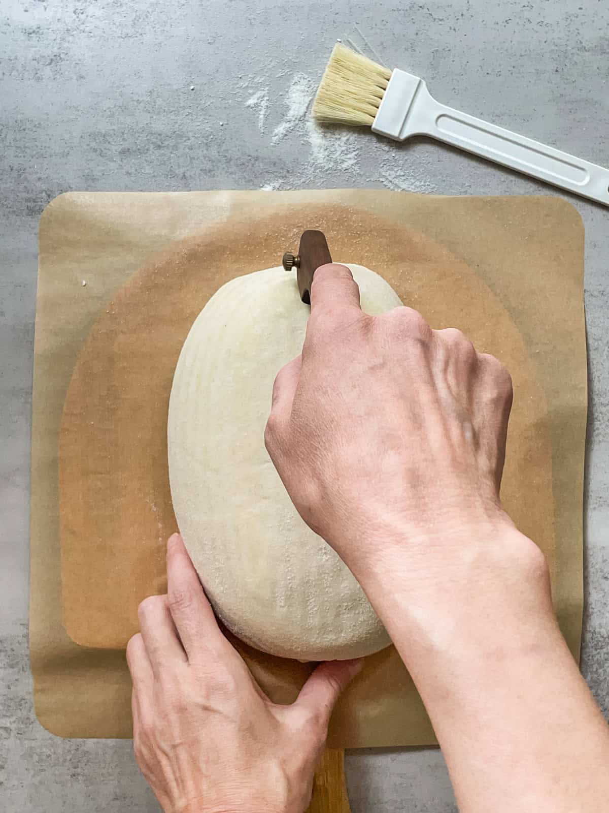 Hand holding a bread lame, ready for scoring.
