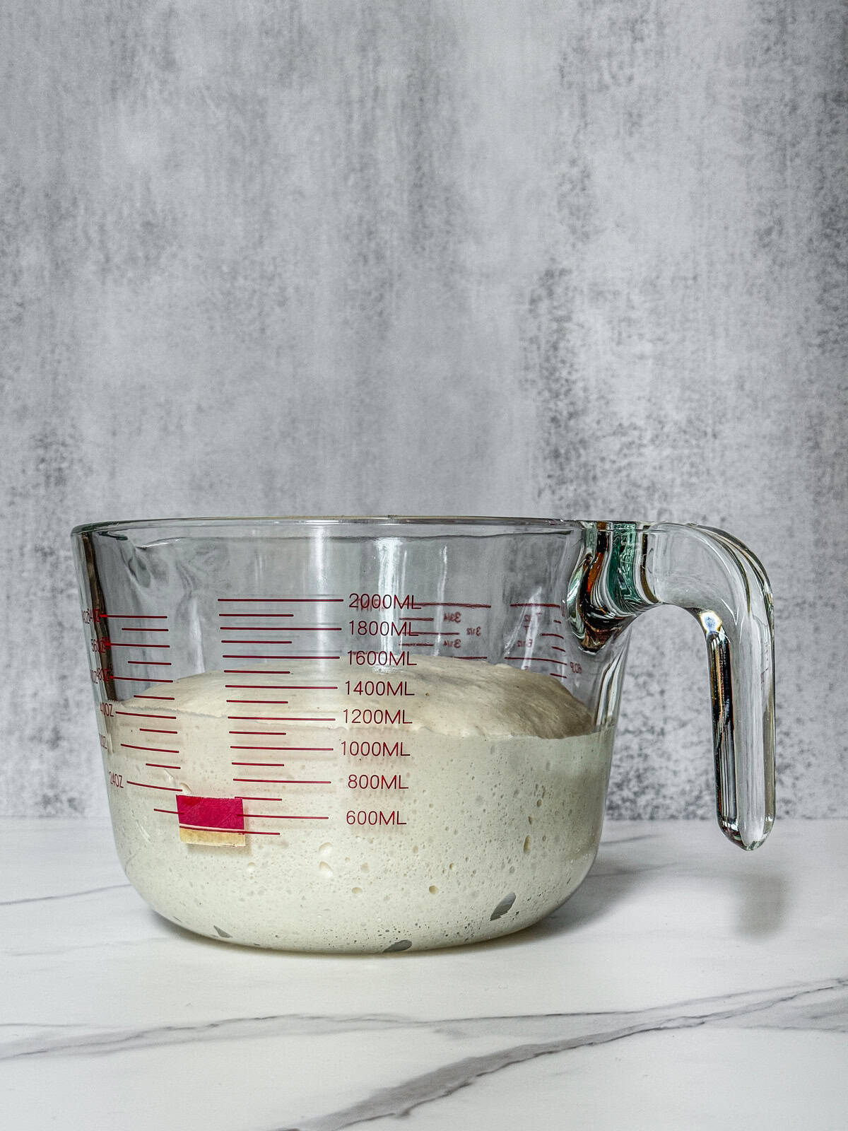 Dough in a measuring cup, end of fermentation, front view.