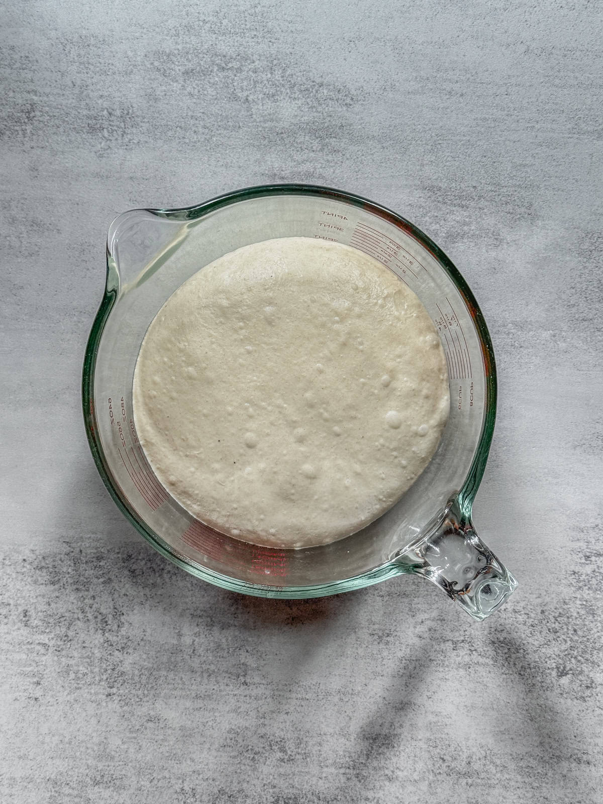Dough in a measuring cup, end of fermentation, overhead view.