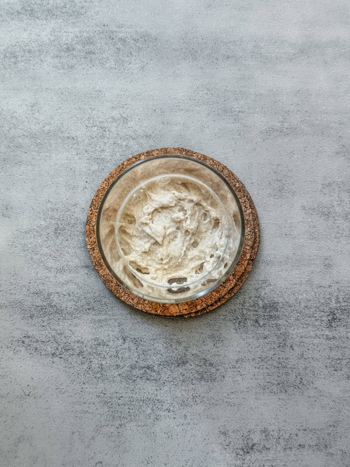 Jar of sourdough starter on day 1 morning after adding bread flour, overhead view.