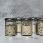 Jars showing sourdough starter at different stages of creation.