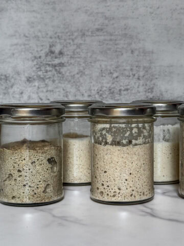 Jars showing sourdough starter at different stages of creation.
