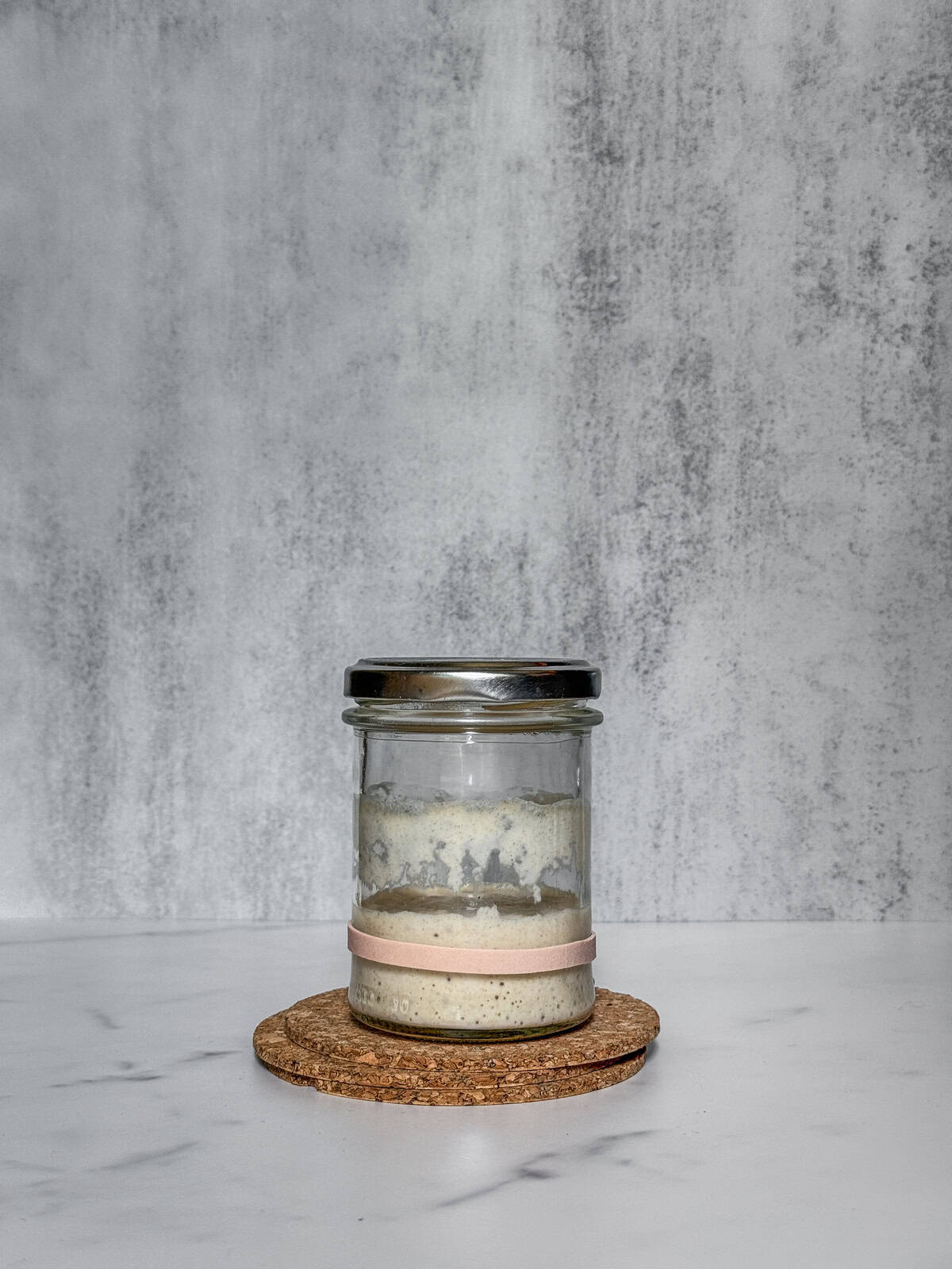 Hungry sourdough starter in a jar with streaks on the sides.