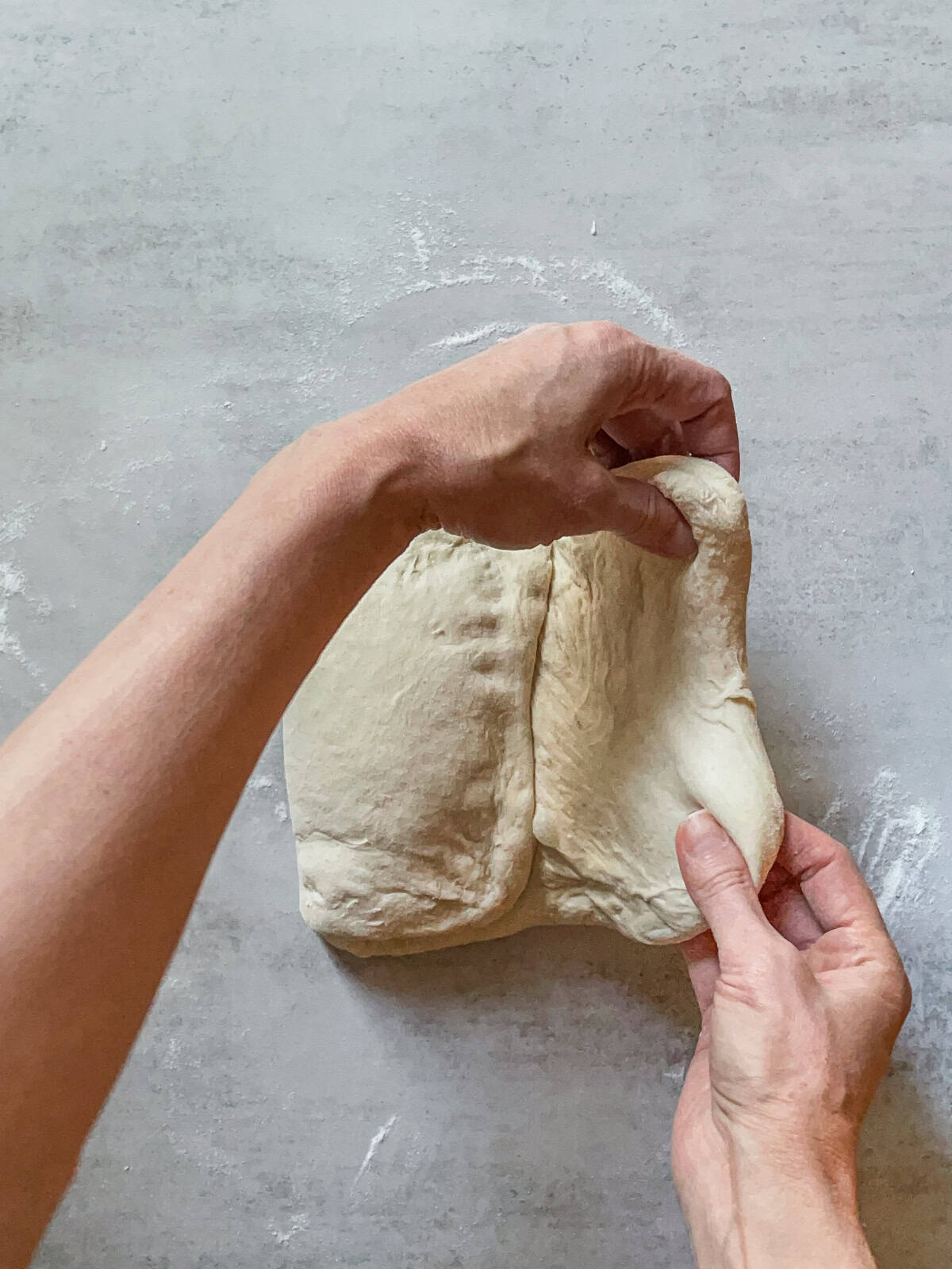 Hands folding the right side of the dough to the center.