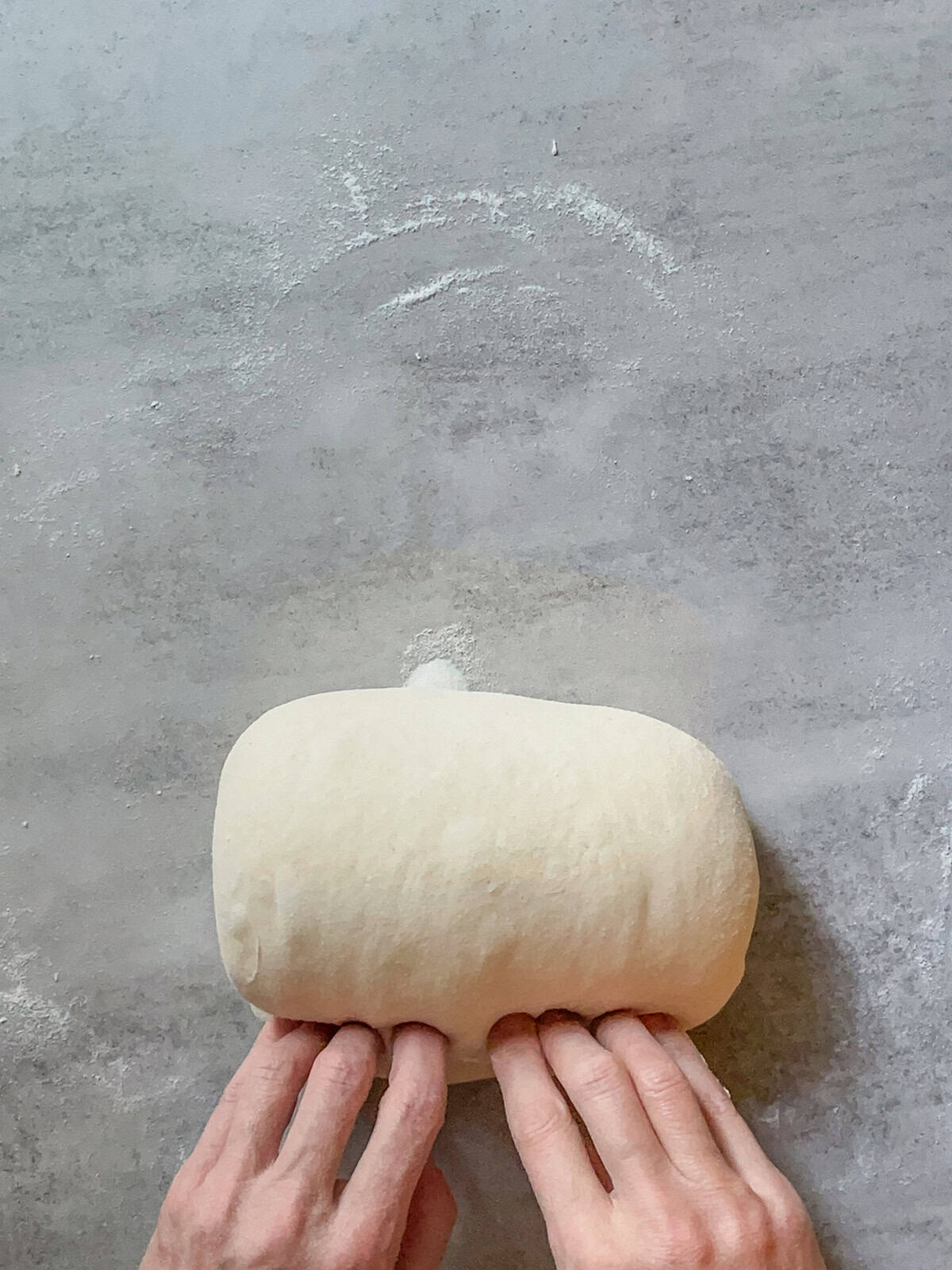 Hands finishing the roll, shaping the dough tightly.