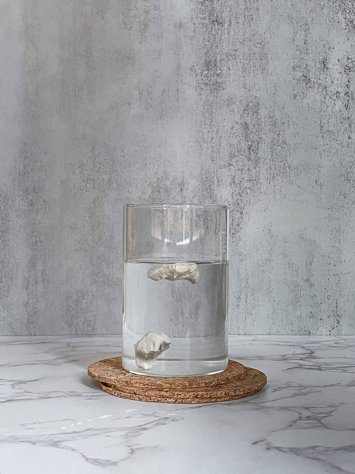 Dough floating in a glass of water, with another piece at the bottom.