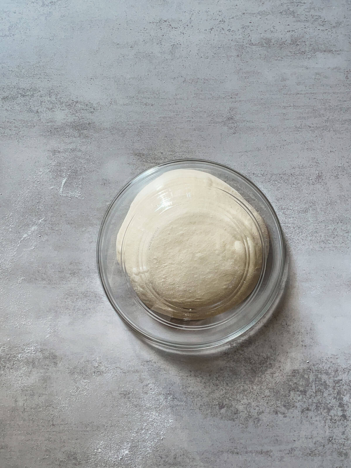 Bread dough covered with a glass mixing bowl.