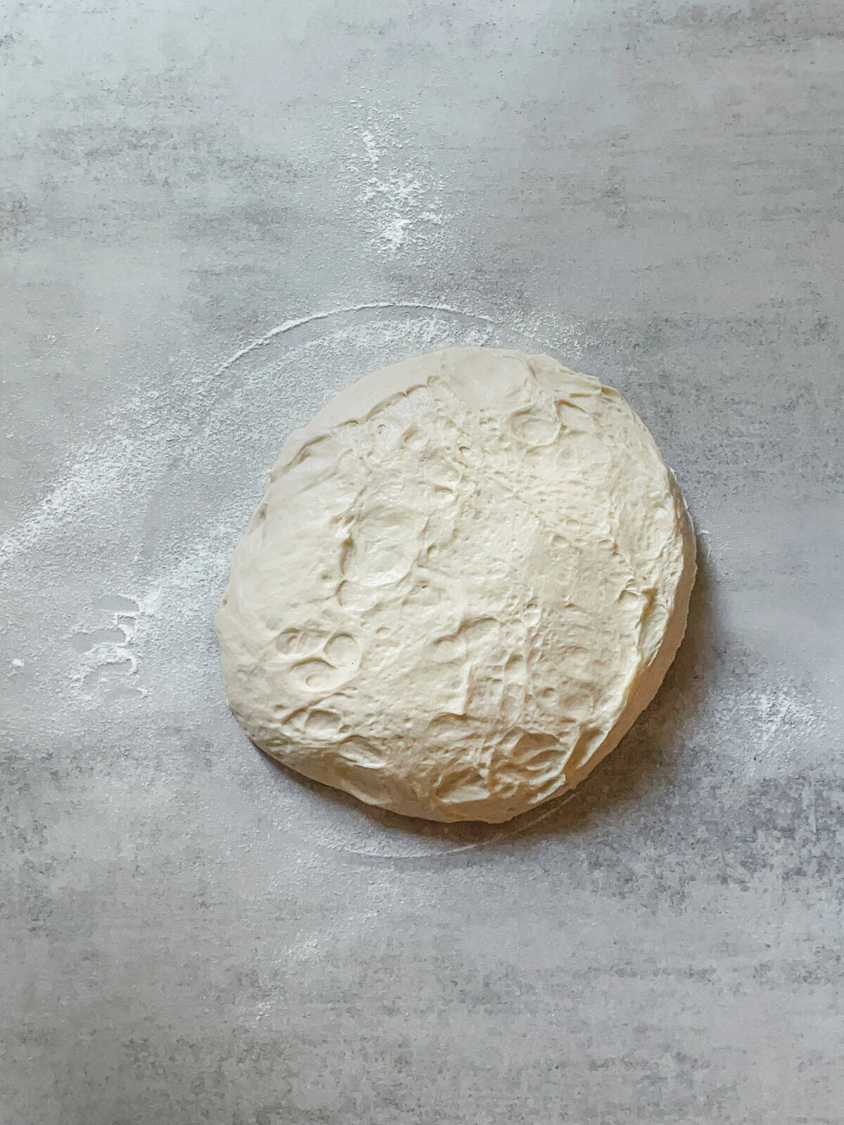Fermented bread dough with sticky side up on a table.