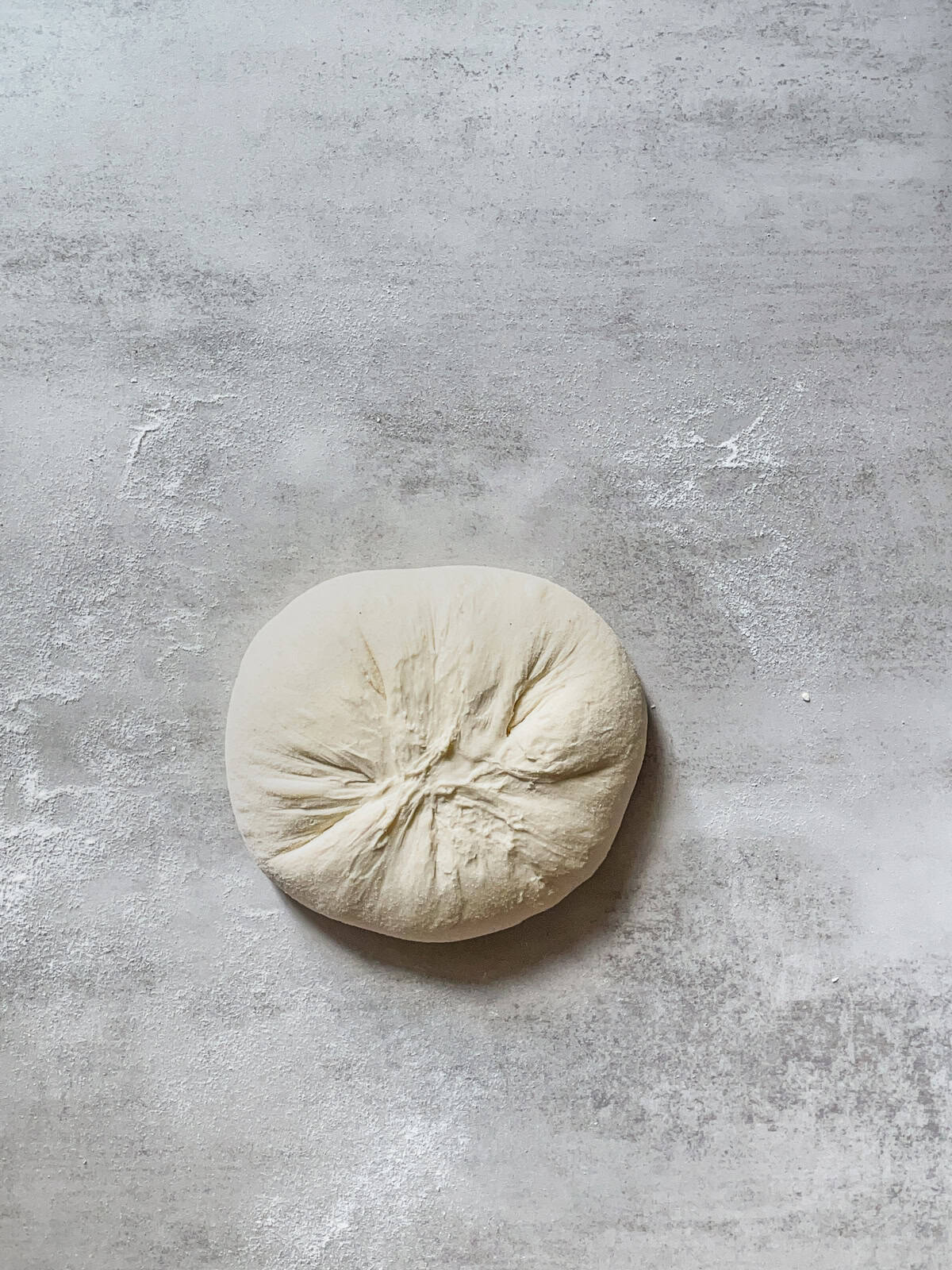 Shaped sourdough boule, seam side up, on a table.