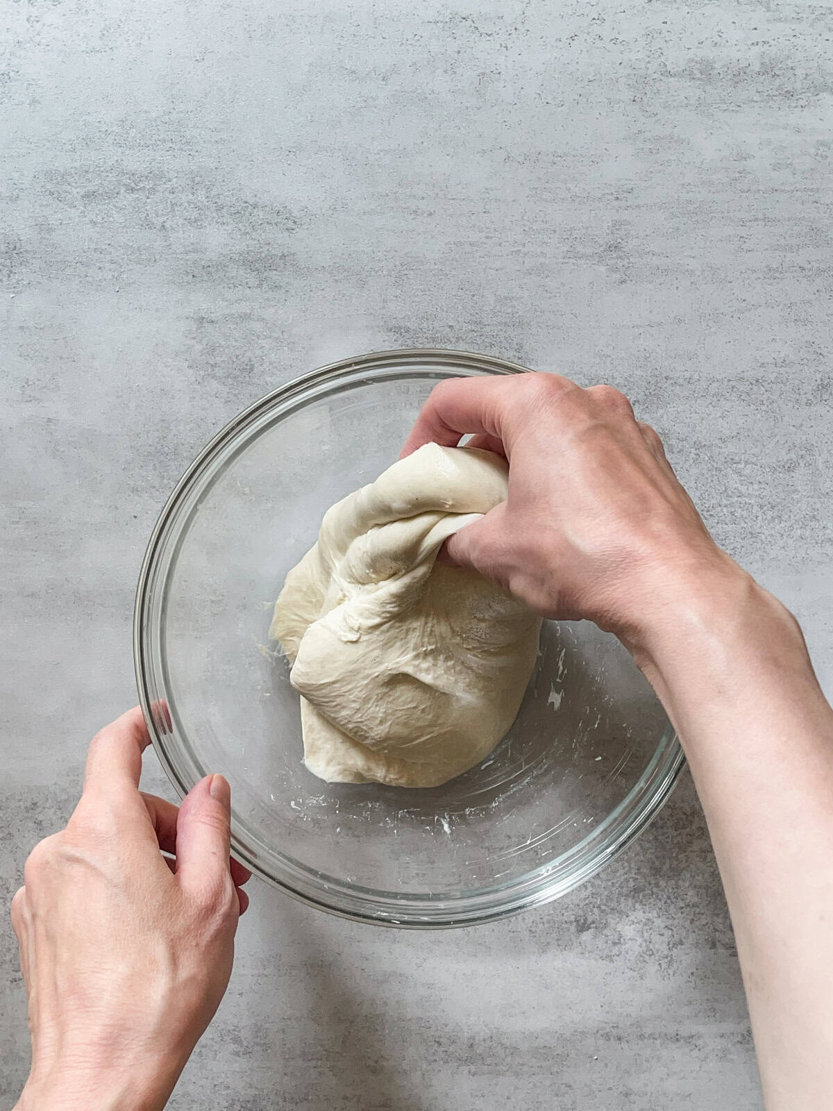 Hand pulling the dough during stretch and folds.