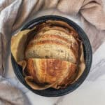 Best homemade sourdough bread sliced in a roasting pan with a towel.