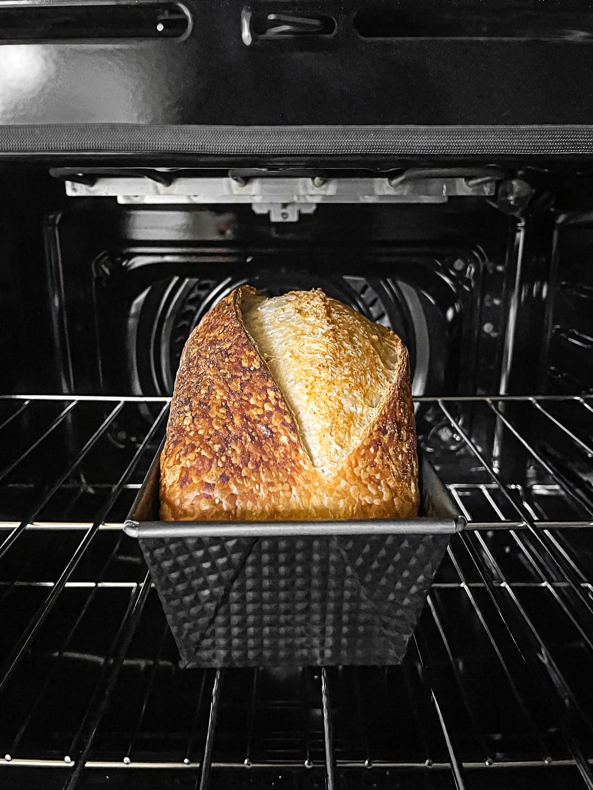 Sourdough bread in a loaf pan in the oven.