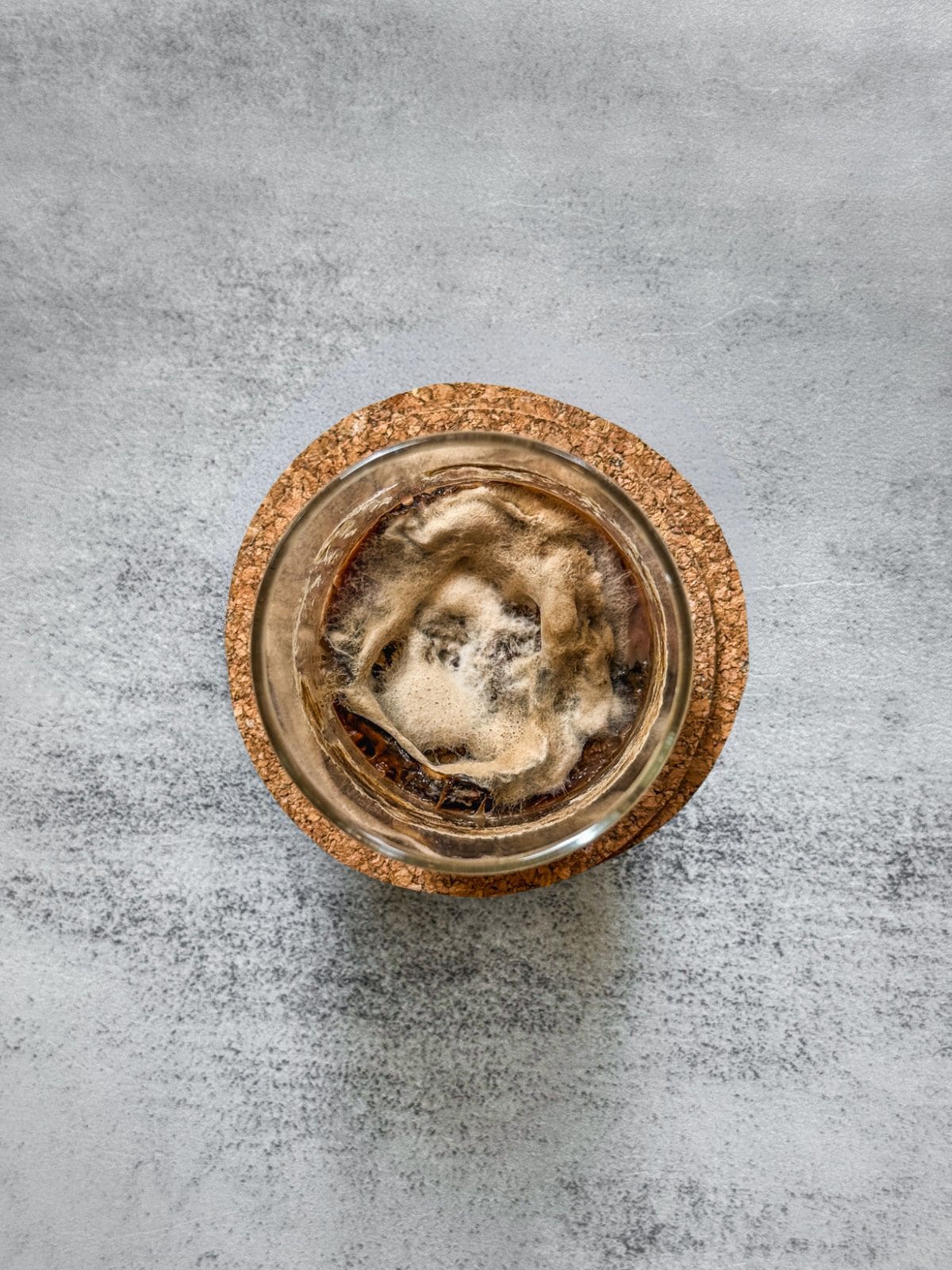 A jar with mold on sourdough starter, showing fuzzy, raised patches.