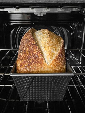 Loaf of sourdough bread in a loaf pan inside the oven.