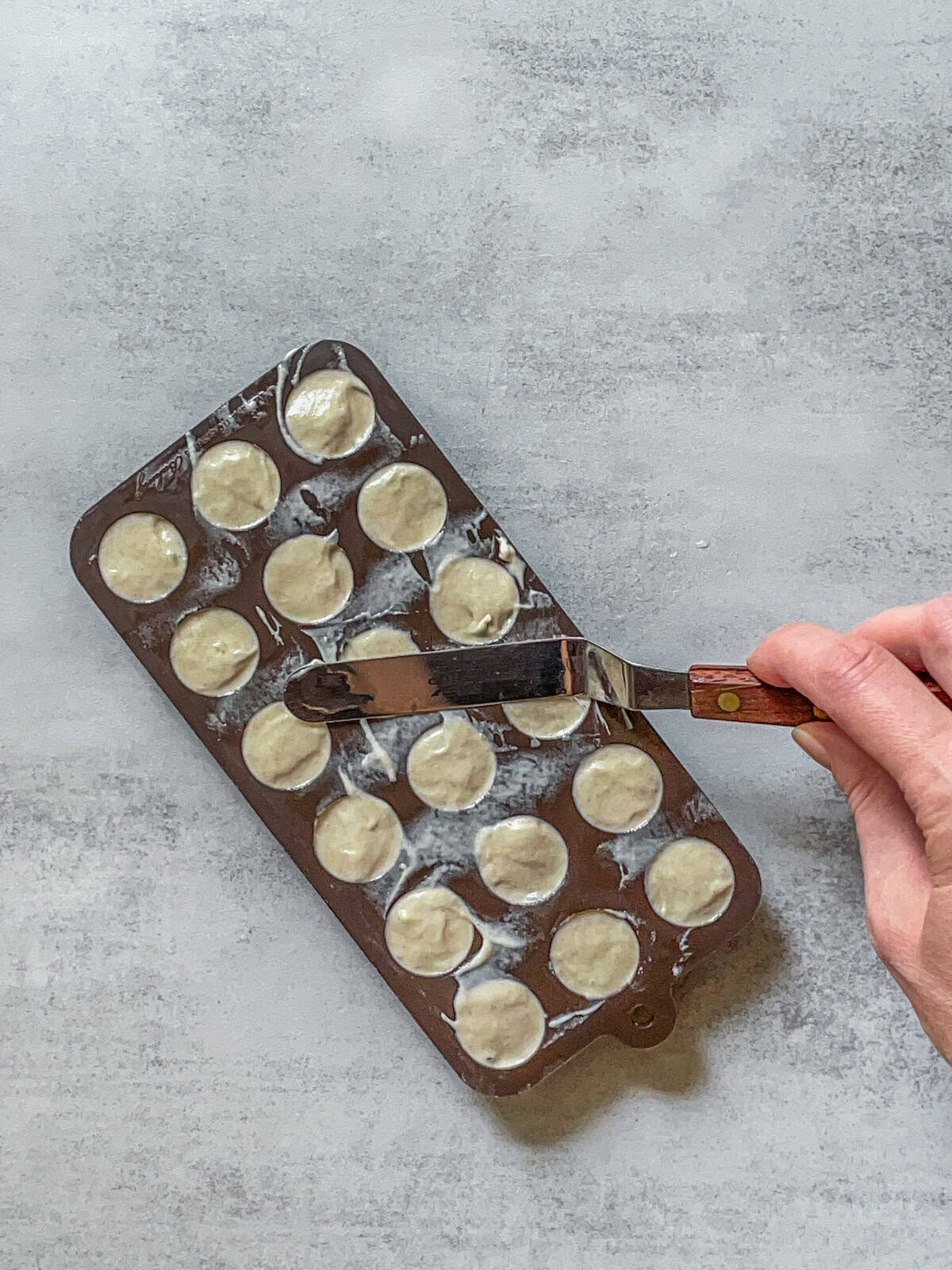 Sourdough starter in a silicone mold with a small offset spatula in hand.