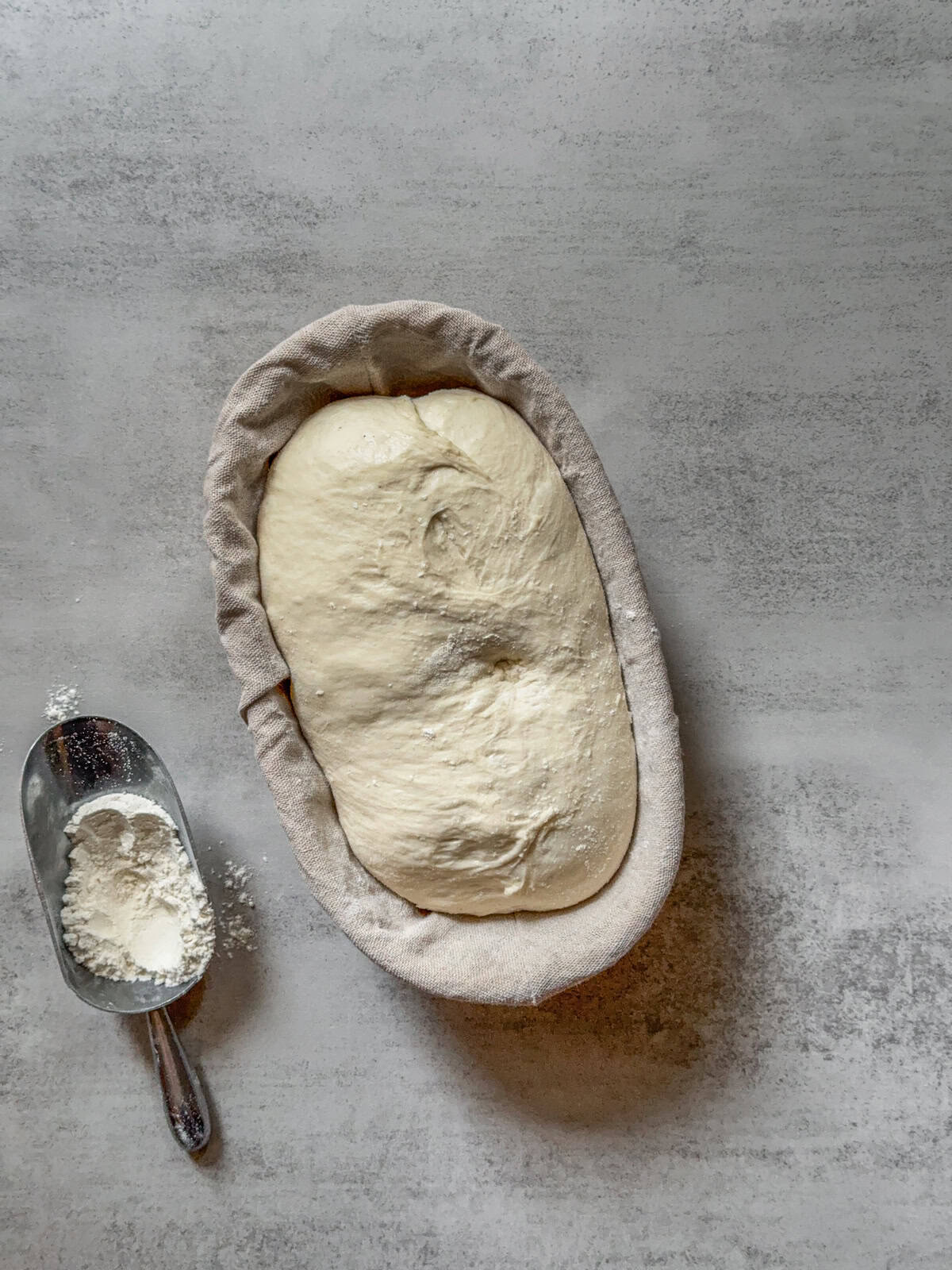 Dough in a banneton with a dent that has sprung back partially.