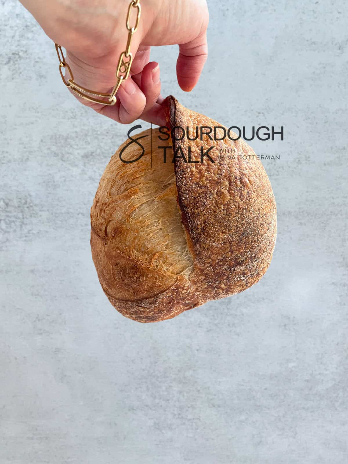 Sourdough loaf showing a finger lifting the sourdough ear.