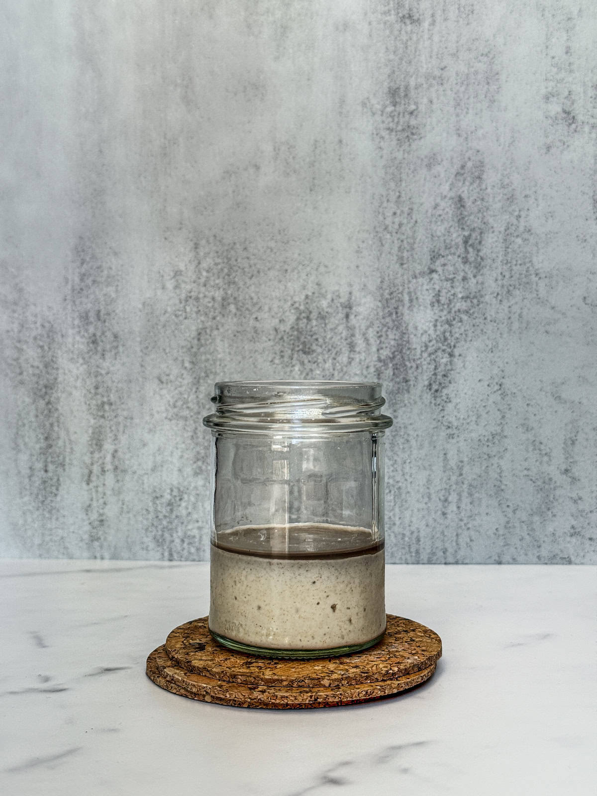 A jar of sourdough starter hooch forming on top of neglected starter.
