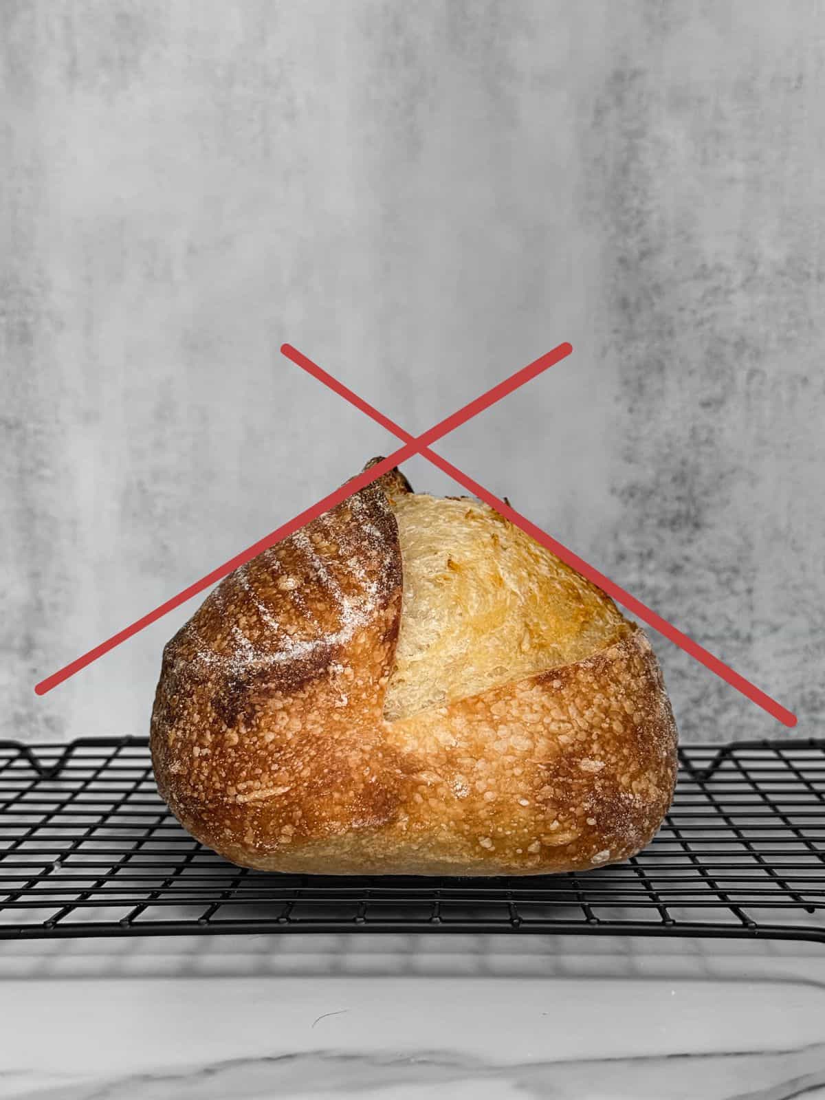 Triangle-shaped underproofed sourdough bread loaf on a wooden board.