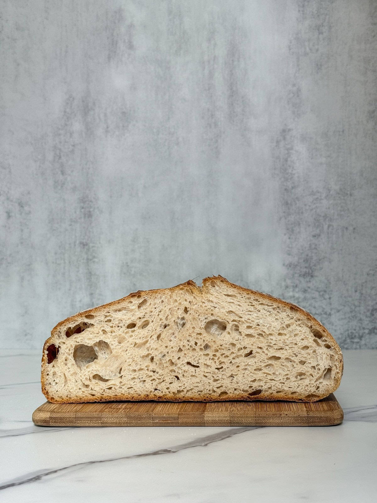 Severely overproofed sourdough crumb on a wooden board.