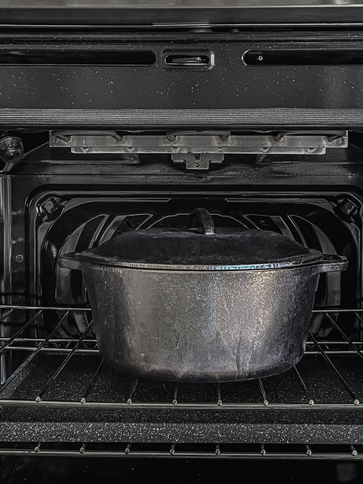 Dutch oven inside the oven with a baking sheet underneath.