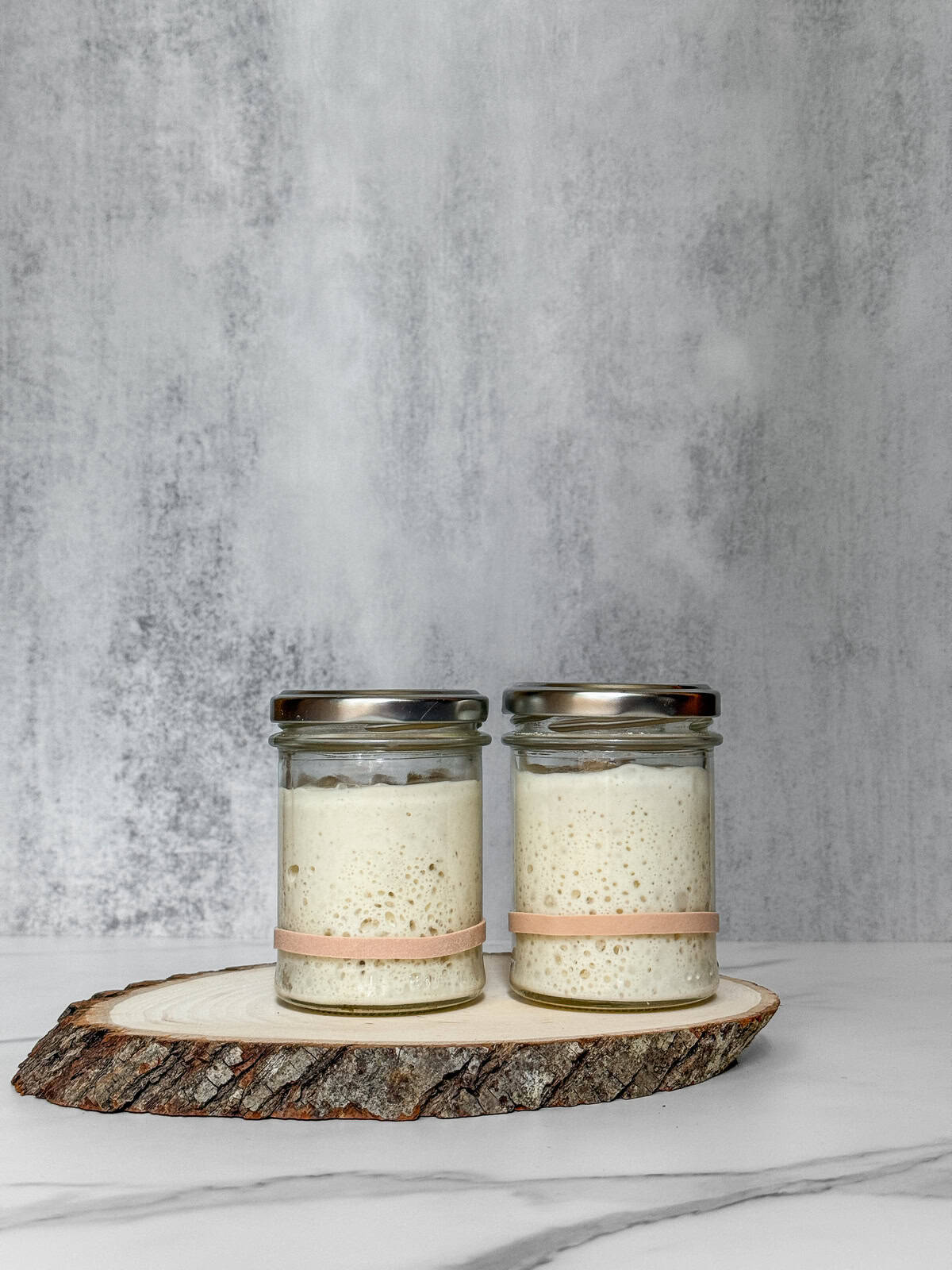 Two glass jars showing a liquid vs. stiff sourdough starter comparison.
