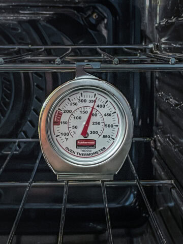 n oven thermometer placed inside an oven, showing a clear 360°F reading.