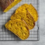 Sliced turmeric sourdough bread loaf on a wire rack.