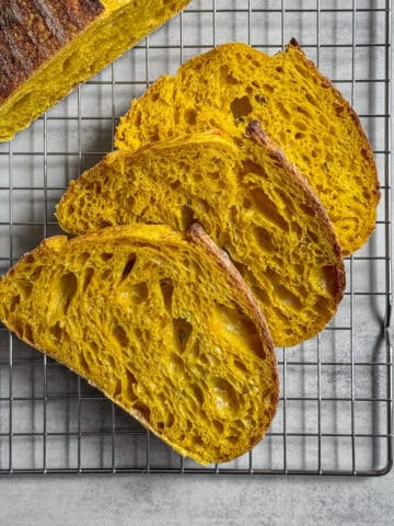 Sliced turmeric sourdough bread loaf on a wire rack.