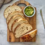 Fresh overnight sourdough bread sliced on a cutting board with guacamole.