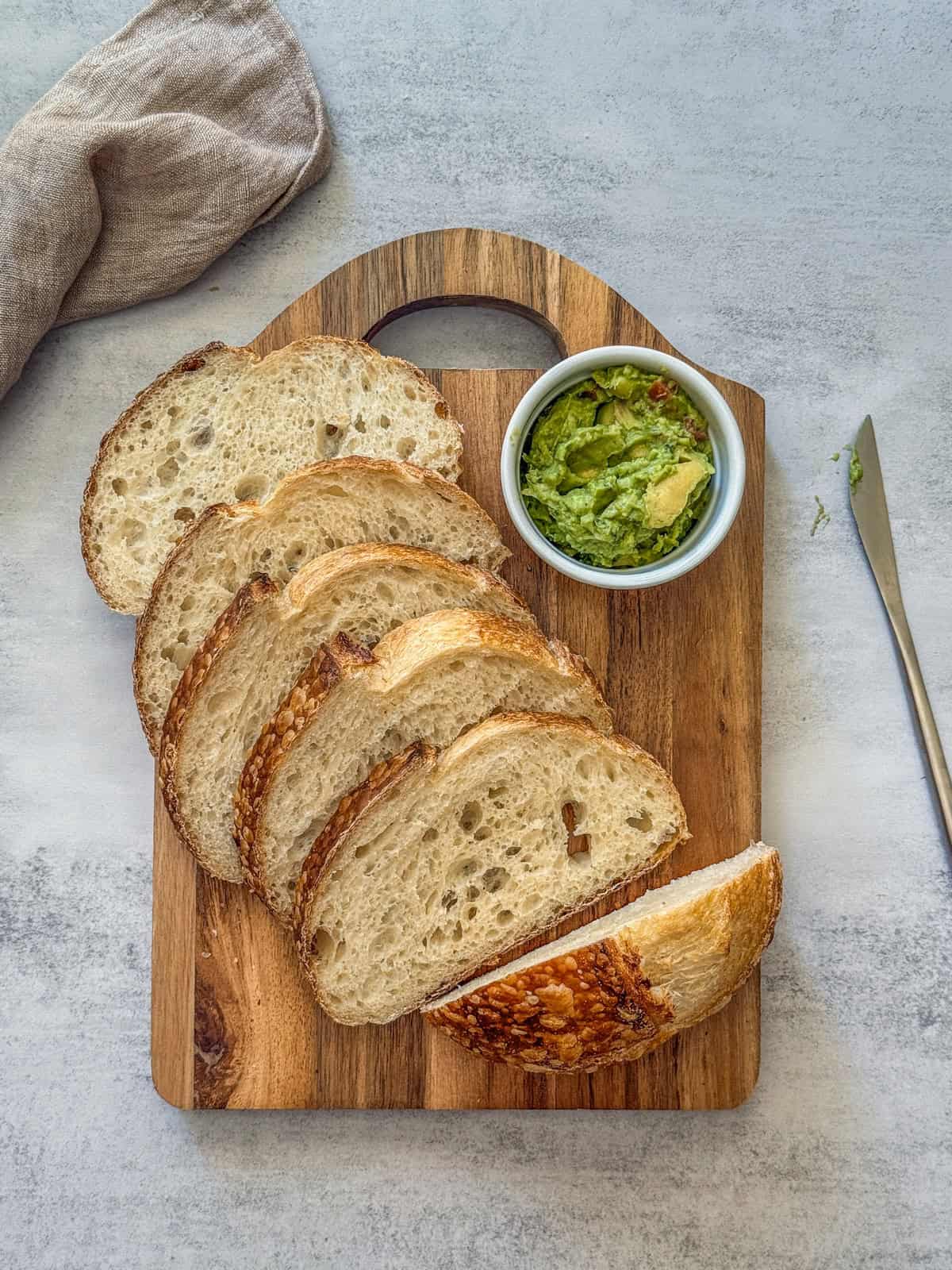 Overnight sourdough bread sliced on a cutting board with guacamole.
