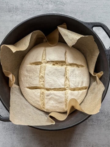 Square slash on sourdough dough in a parchment-lined Dutch oven.
