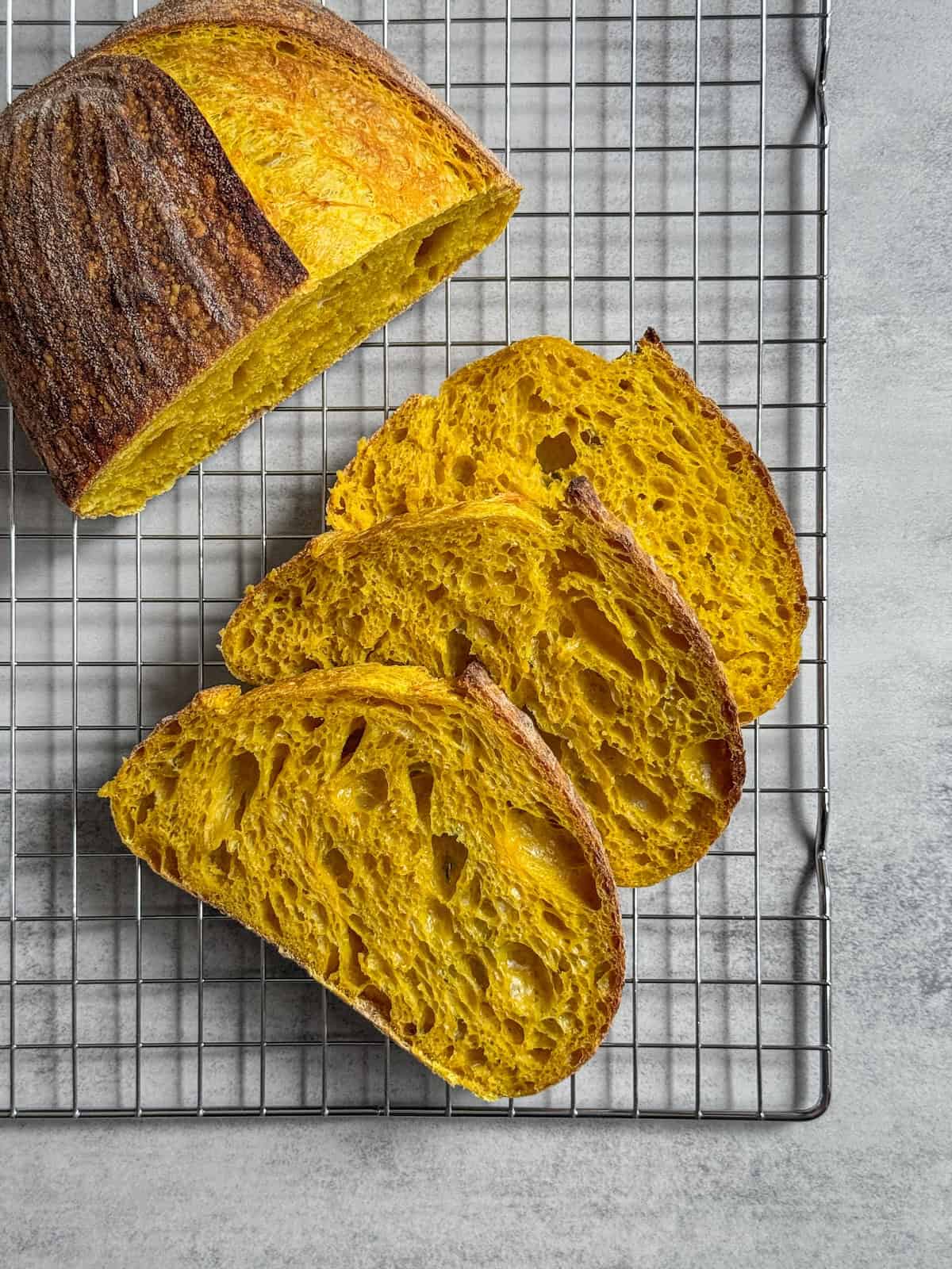 Sliced turmeric sourdough bread on a wire rack.