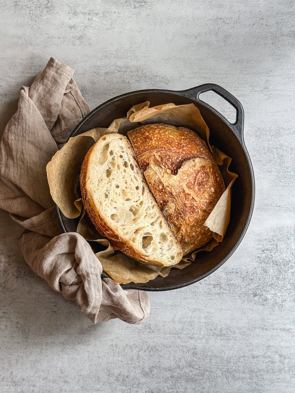 Fresh unloafed sourdough bread sliced in half in a Dutch oven.