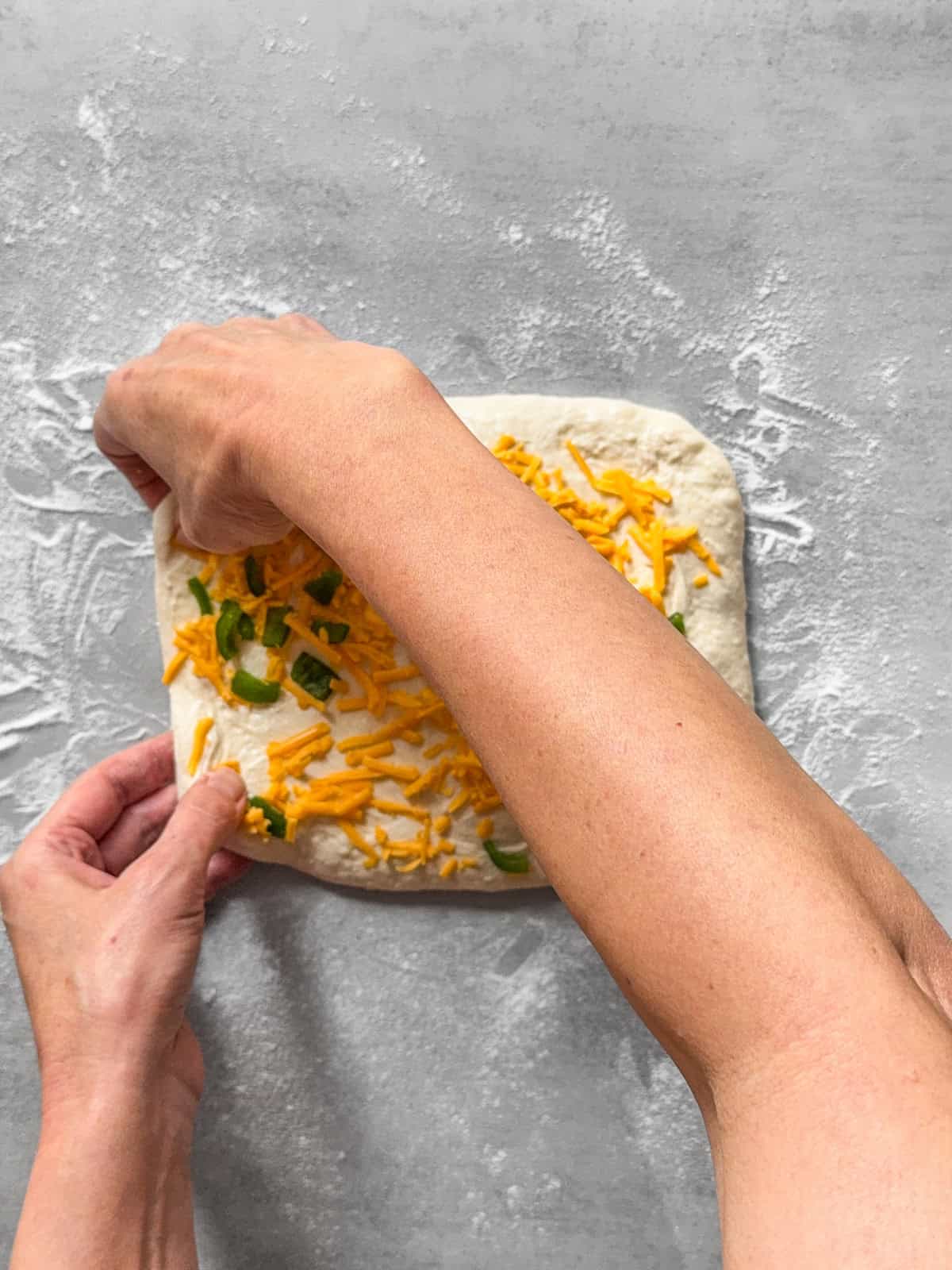 Hands taking the left side of the dough to the center.