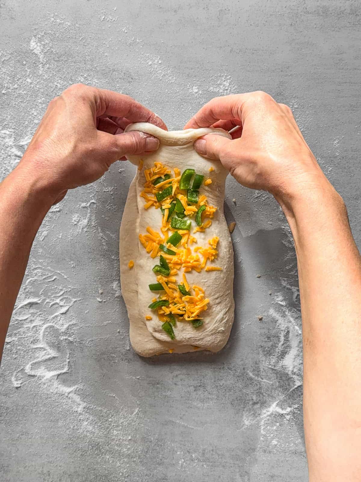 Hands pulling the top of the dough.