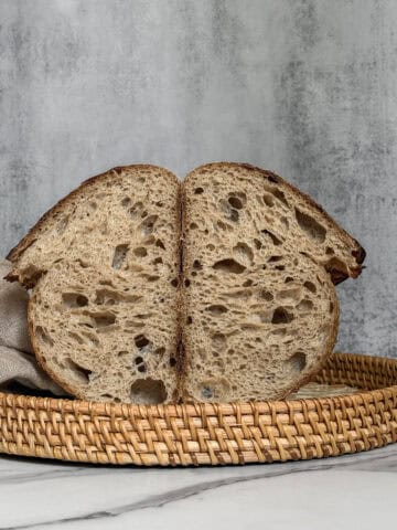 Halved artisan sourdough bread in a rattan tray.