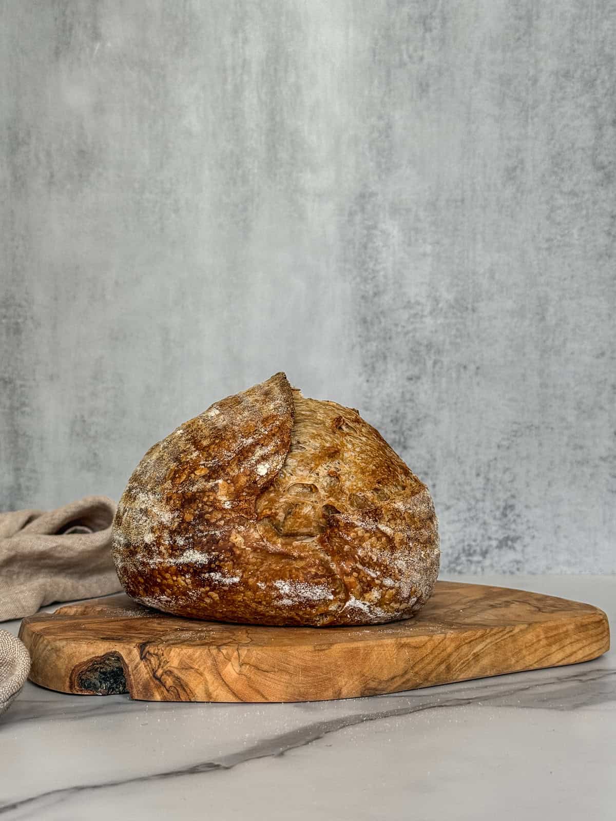 A loaf of artisan sourdough bread on a wooden board.