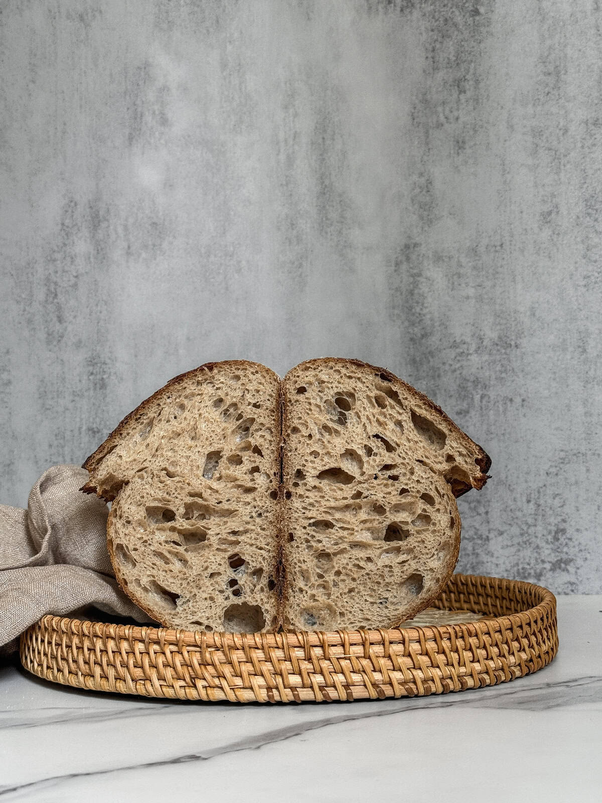 Halved artisan sourdough bread in a serving rattan tray.