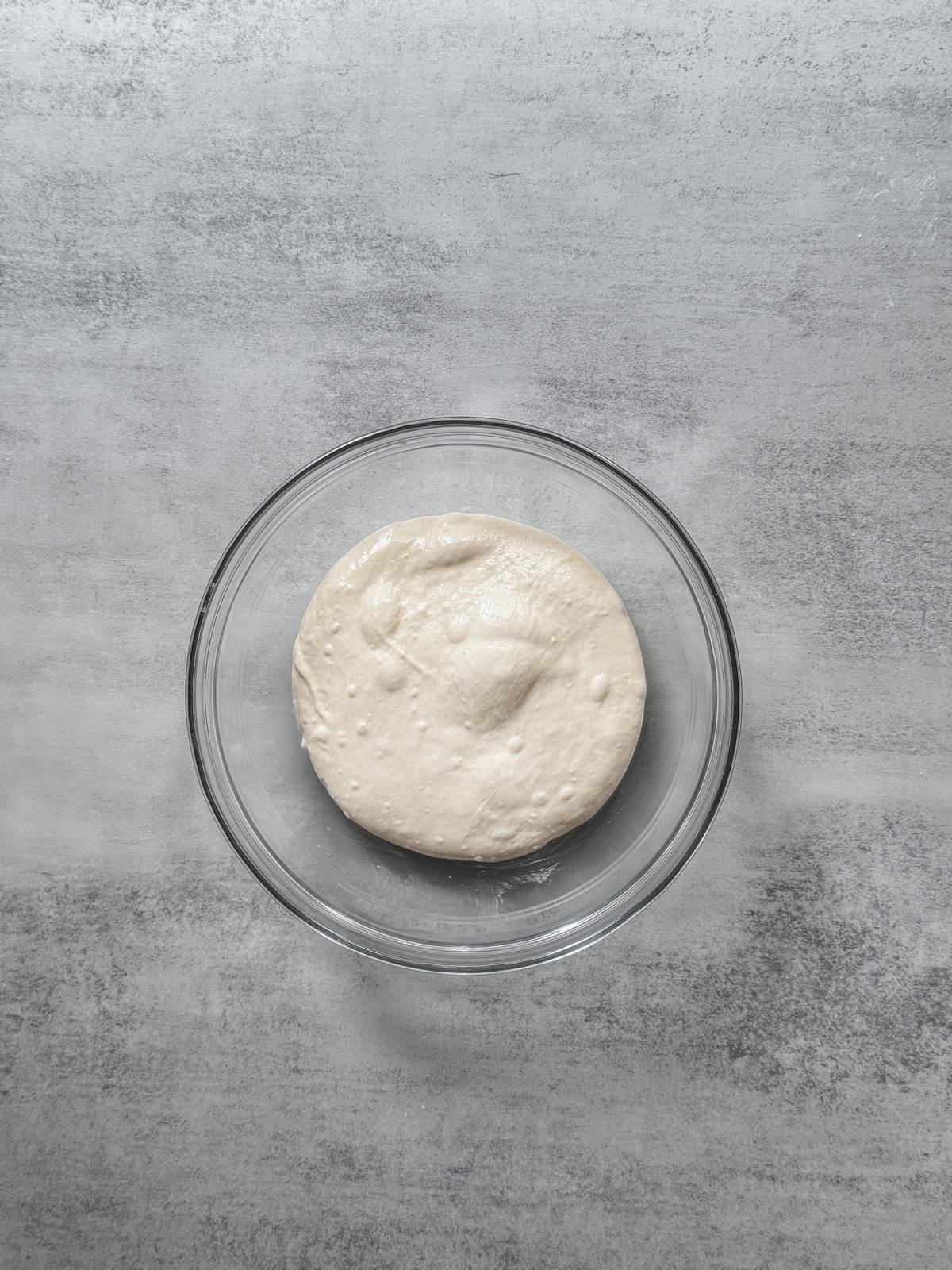 Laminated sourdough in a glass bowl during bulk fermentation.