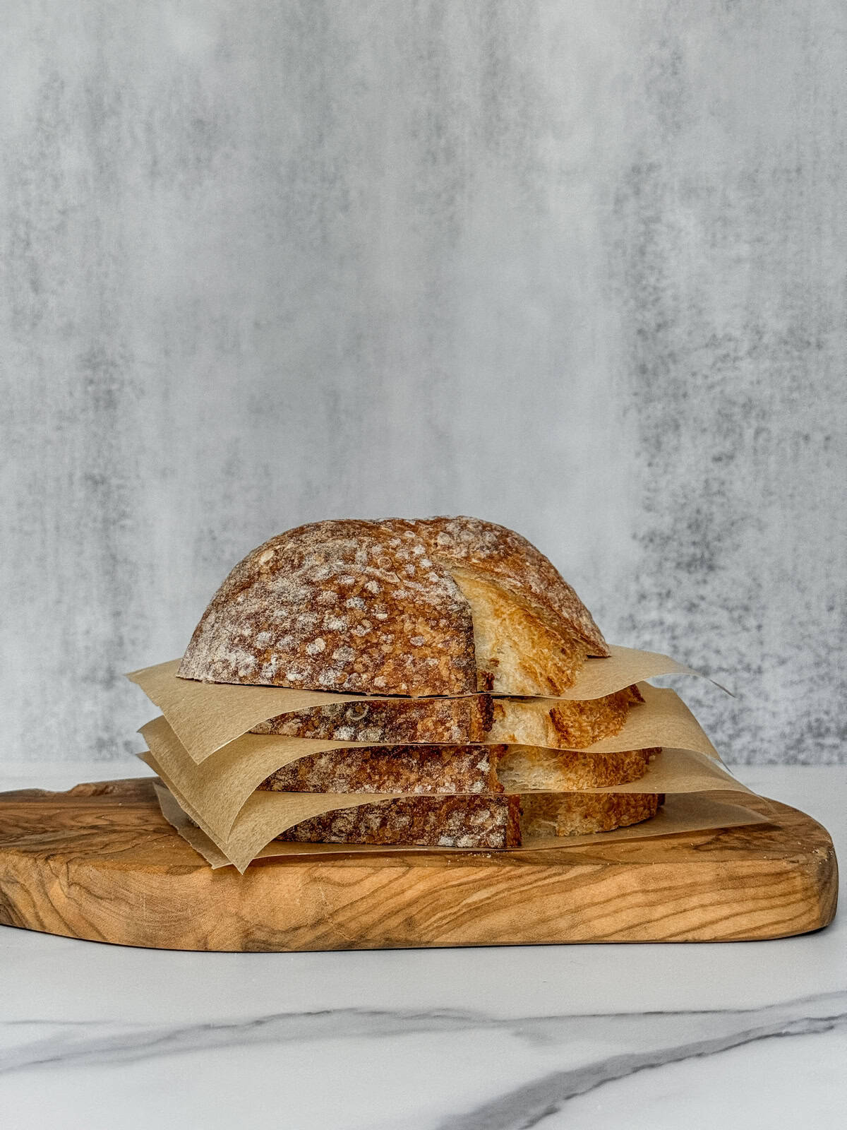 Stacked sourdough bread slices with parchment paper between each slice.